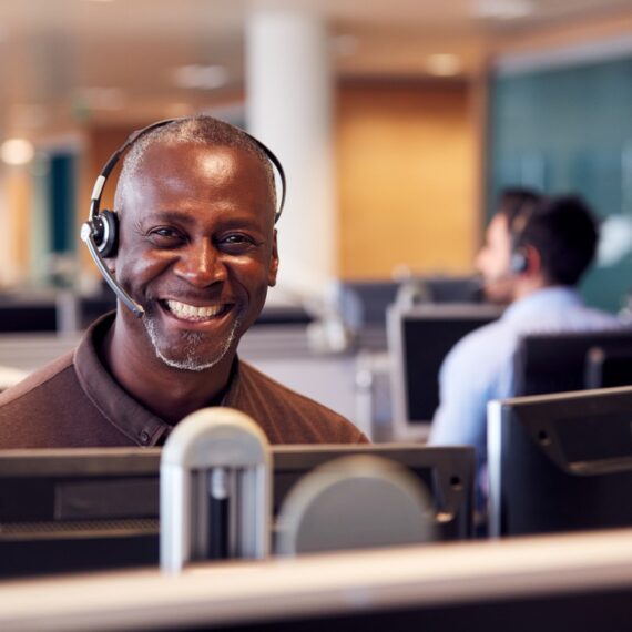 Portrait Of Mature Businessman Wearing Telephone Headset Working In Customer Services Department