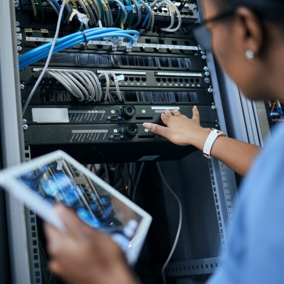 Rearview shot of an unrecognizable female programmer working on a tablet in a server room.